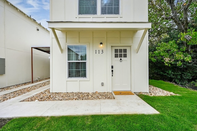 view of exterior entry featuring a lawn and board and batten siding