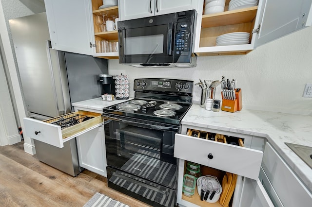 kitchen with white cabinetry, light stone counters, and black appliances