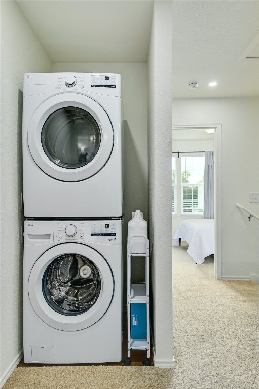 washroom featuring laundry area, stacked washer / drying machine, baseboards, and carpet floors