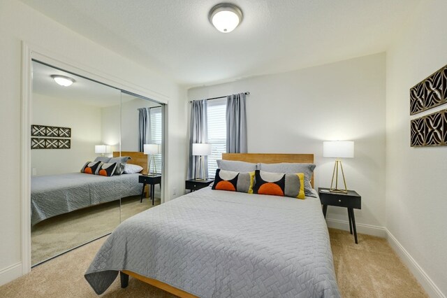 carpeted bedroom with a closet and baseboards