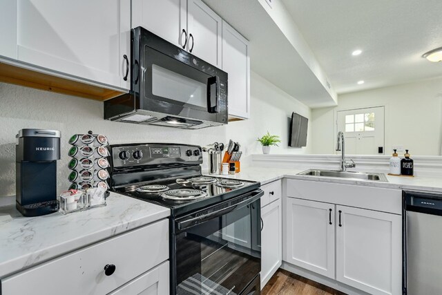 kitchen featuring white cabinetry, black appliances, light stone counters, and a sink