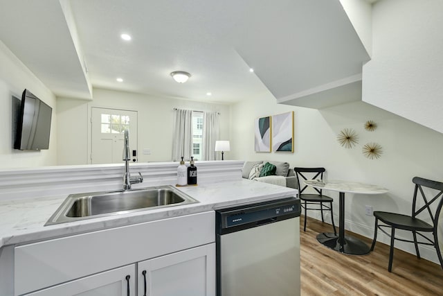 kitchen with dishwasher, sink, light stone counters, and light hardwood / wood-style flooring