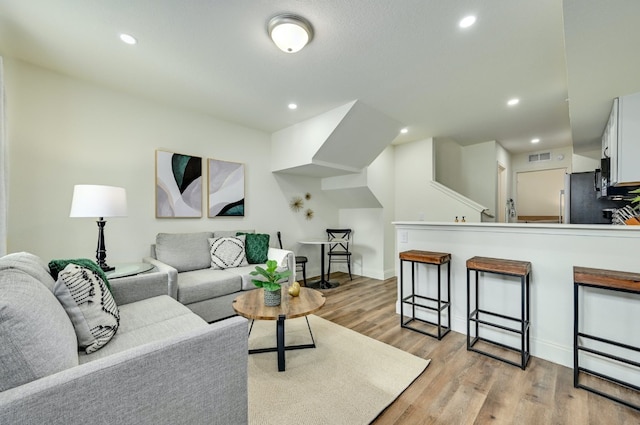 living area featuring light wood-style flooring, recessed lighting, and baseboards