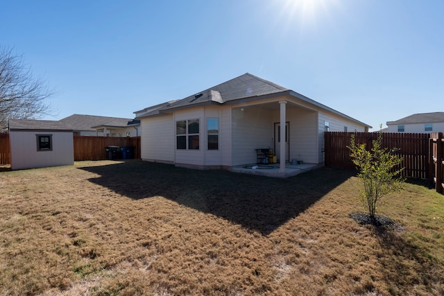 rear view of house with a patio, a lawn, and a shed