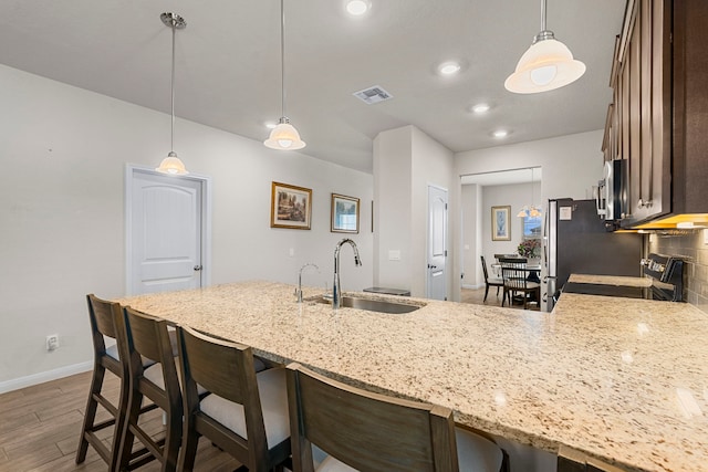 kitchen featuring sink, appliances with stainless steel finishes, pendant lighting, hardwood / wood-style floors, and backsplash