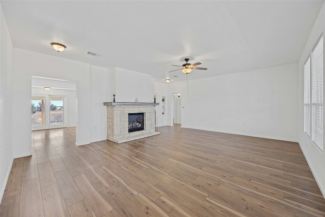 unfurnished living room featuring hardwood / wood-style flooring, ceiling fan, and a fireplace