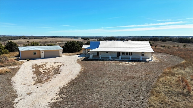 view of front facade featuring a rural view, a garage, and covered porch