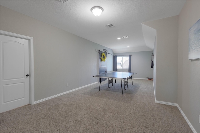 game room featuring lofted ceiling, light colored carpet, and a textured ceiling