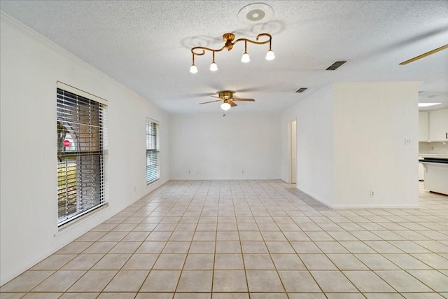 tiled spare room featuring ceiling fan, a textured ceiling, and a wealth of natural light