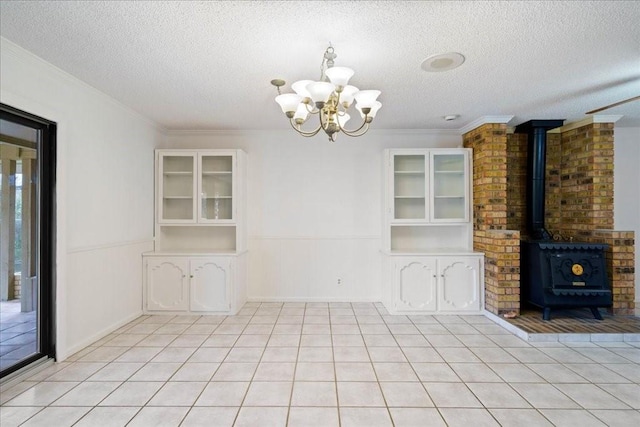 unfurnished dining area featuring a textured ceiling, light tile patterned floors, a wood stove, ornamental molding, and a notable chandelier