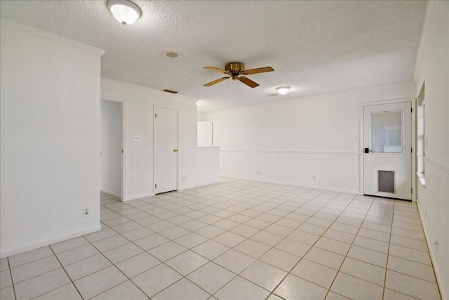 empty room featuring ceiling fan, ornamental molding, a textured ceiling, and light tile patterned flooring