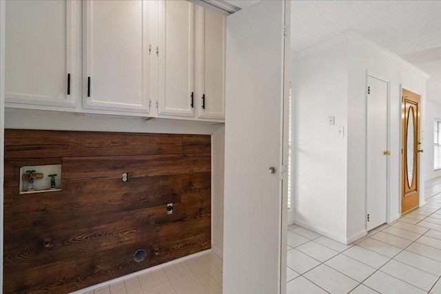 washroom with cabinets, crown molding, washer hookup, and light tile patterned flooring