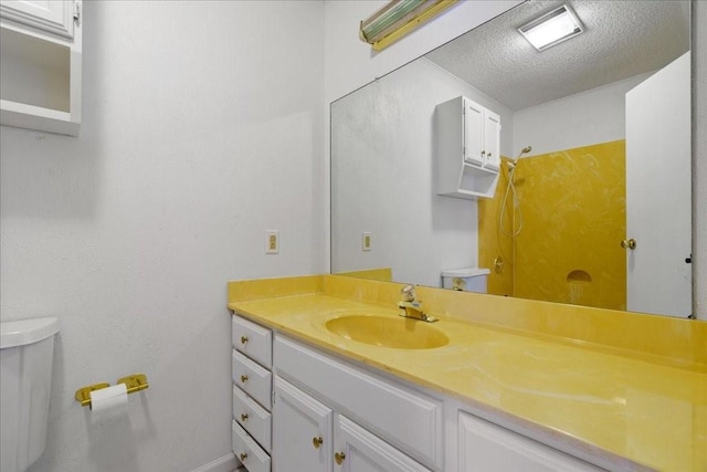 bathroom with vanity, a textured ceiling, and toilet