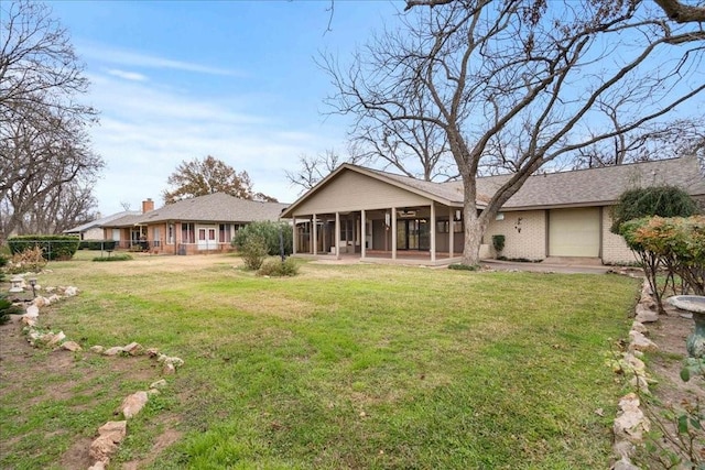 rear view of house featuring a garage, a yard, and a sunroom