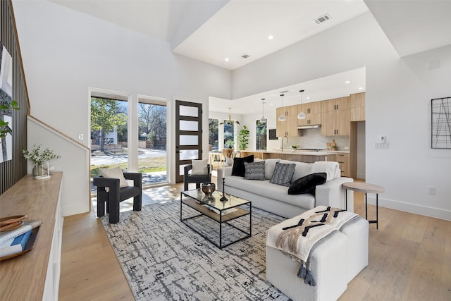 living room with a towering ceiling and light hardwood / wood-style floors