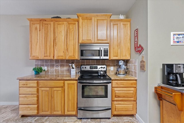 kitchen featuring stainless steel appliances, light brown cabinets, and backsplash