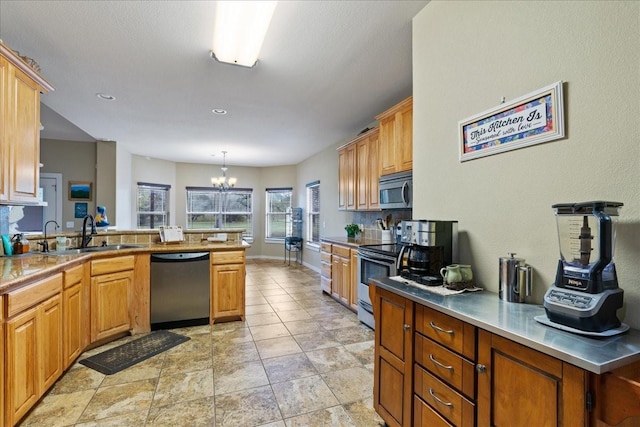 kitchen with sink, a chandelier, appliances with stainless steel finishes, kitchen peninsula, and pendant lighting