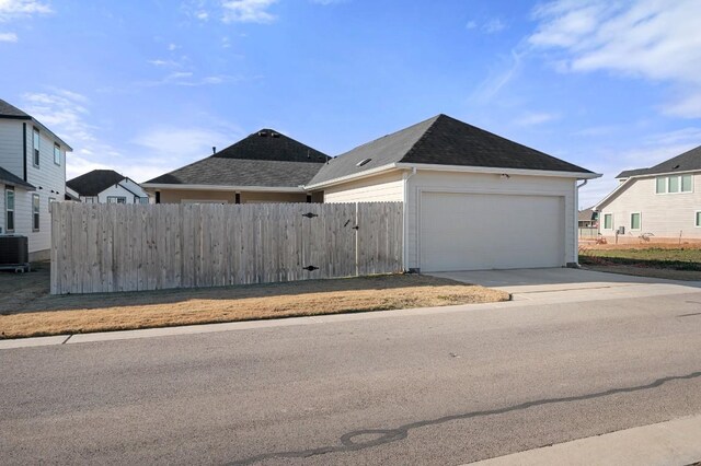 305 Ravens Crest Dr, Hutto, TX 78634 - view of side of home featuring driveway, a garage, a shingled roof, and cooling unit