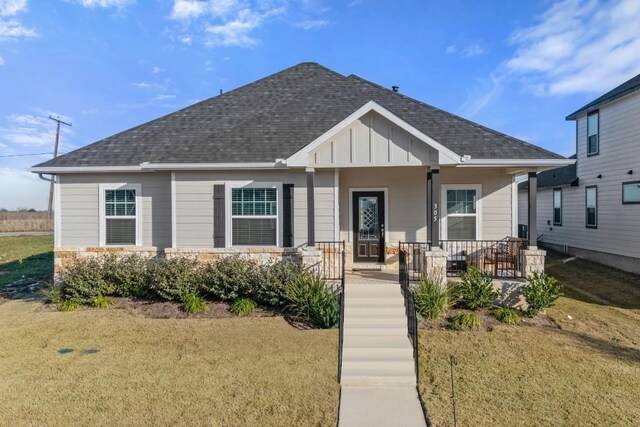 305 Ravens Crest Dr, Hutto, TX 78634 - view of front of house with board and batten siding, covered porch, a shingled roof, and a front lawn