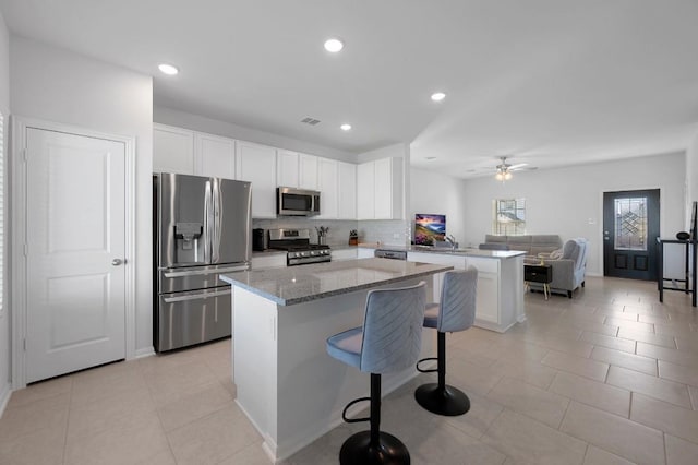 305 Ravens Crest Dr, Hutto, TX 78634 - kitchen with appliances with stainless steel finishes, a kitchen island, a peninsula, white cabinets, and open floor plan