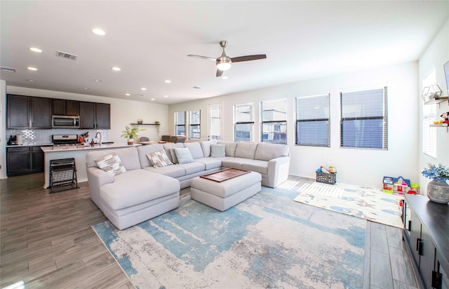 living room featuring ceiling fan, sink, and light hardwood / wood-style flooring