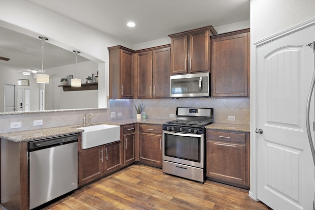 kitchen featuring dark wood-type flooring, sink, light stone counters, tasteful backsplash, and stainless steel appliances