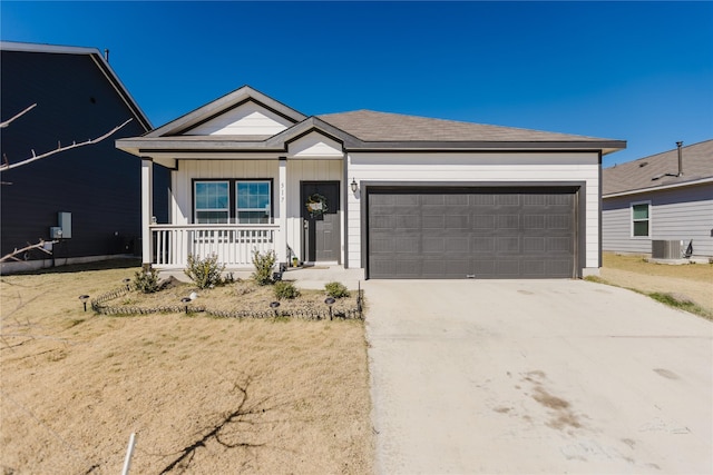 ranch-style home featuring cooling unit, a garage, a front lawn, and a porch