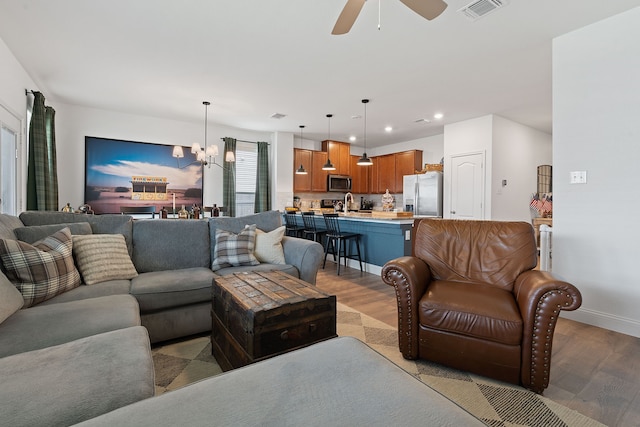 living room with sink, ceiling fan with notable chandelier, and light hardwood / wood-style floors