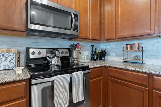 kitchen featuring stainless steel appliances, light stone counters, and decorative backsplash