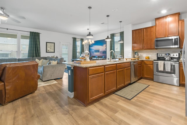 kitchen featuring stainless steel appliances, hanging light fixtures, sink, and kitchen peninsula