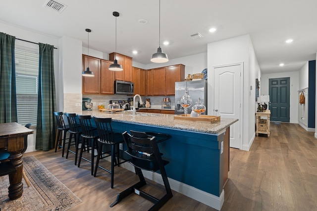 kitchen with sink, a breakfast bar, appliances with stainless steel finishes, hanging light fixtures, and kitchen peninsula