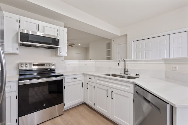 kitchen with sink, light hardwood / wood-style flooring, appliances with stainless steel finishes, white cabinets, and kitchen peninsula