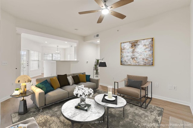 living room featuring visible vents, ceiling fan, baseboards, and wood finished floors