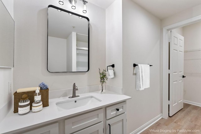 bathroom with baseboards, wood finished floors, and vanity