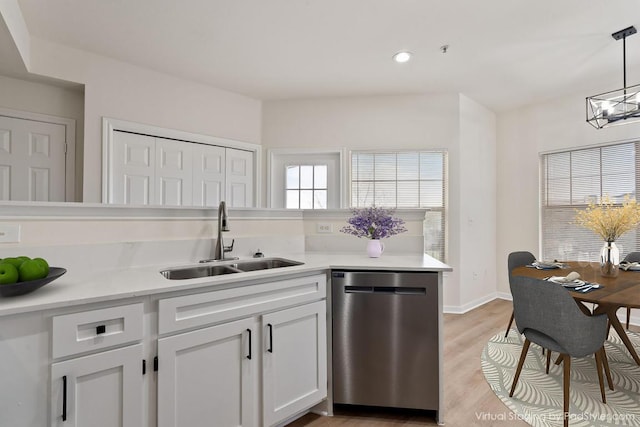 kitchen featuring a wealth of natural light, light countertops, dishwasher, and a sink