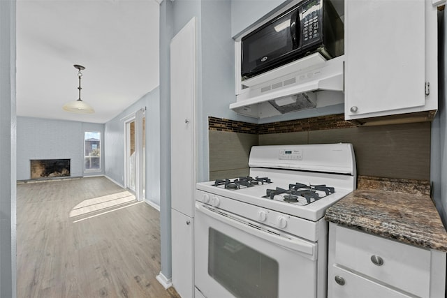 kitchen with a brick fireplace, light wood-type flooring, white range with gas cooktop, pendant lighting, and white cabinets