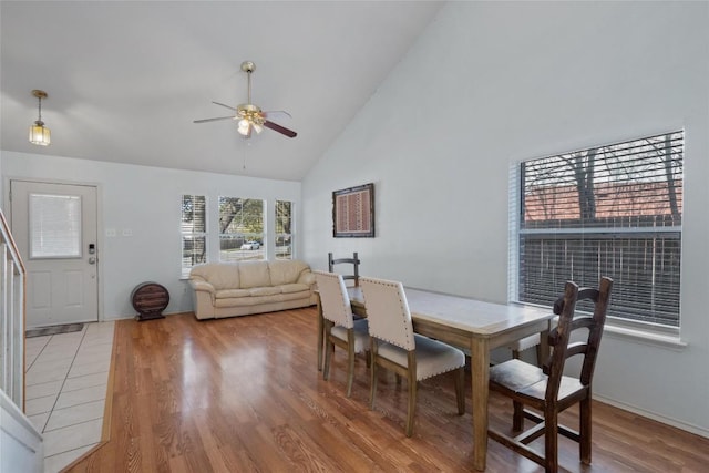 dining room featuring light wood-style floors, high vaulted ceiling, and a ceiling fan