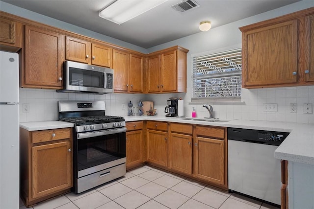 15101 Sweet Caddies Dr, Pflugerville, TX 78660 - kitchen featuring stainless steel appliances, a sink, light countertops, tasteful backsplash, and brown cabinets