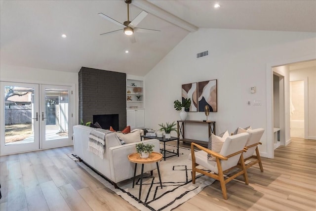 living area featuring visible vents, light wood-style floors, beamed ceiling, and french doors