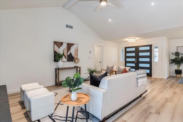 living room with ceiling fan, high vaulted ceiling, beam ceiling, and light hardwood / wood-style flooring