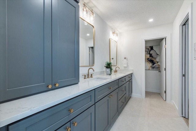 bathroom featuring double vanity, a textured ceiling, baseboards, and a sink