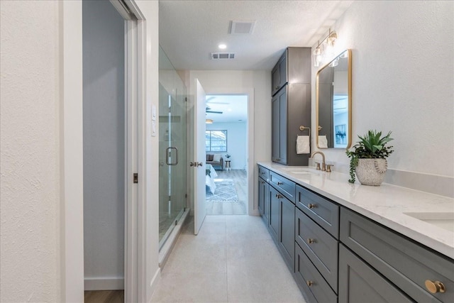 ensuite bathroom featuring double vanity, visible vents, a shower stall, and a sink