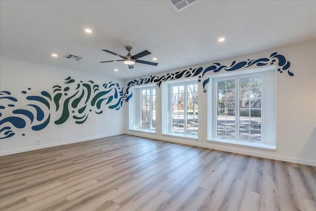 empty room featuring visible vents, baseboards, and light wood finished floors