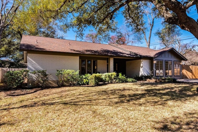 view of front of home with a front lawn, fence, and brick siding