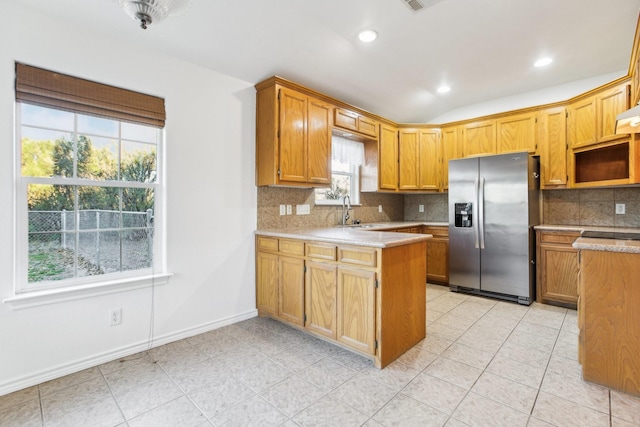 kitchen featuring sink, backsplash, vaulted ceiling, and stainless steel refrigerator with ice dispenser