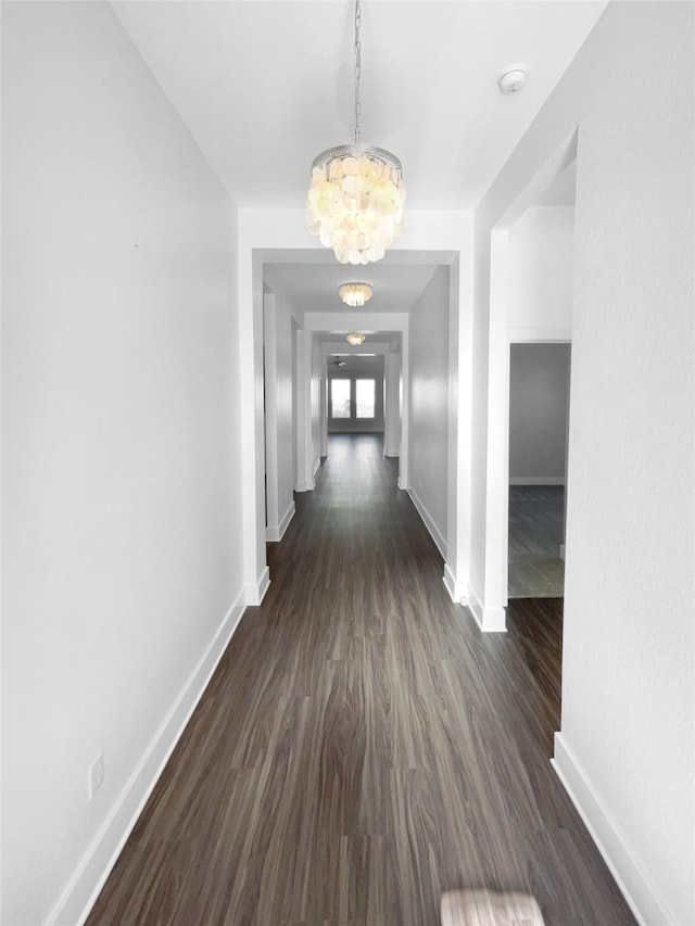 hall featuring dark wood-type flooring and a chandelier