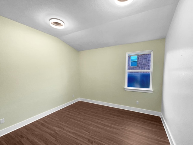 spare room featuring vaulted ceiling and dark wood-type flooring