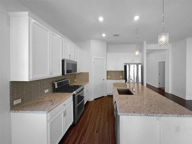 2120 Prairie Oaks Dr, Georgetown, TX 78628 - kitchen with appliances with stainless steel finishes, white cabinetry, dark wood-style flooring, an island with sink, and recessed lighting
