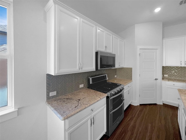 kitchen with appliances with stainless steel finishes, dark hardwood / wood-style floors, tasteful backsplash, light stone countertops, and white cabinets