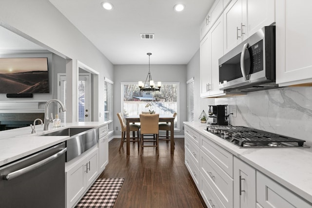 kitchen with white cabinetry, hanging light fixtures, and stainless steel appliances